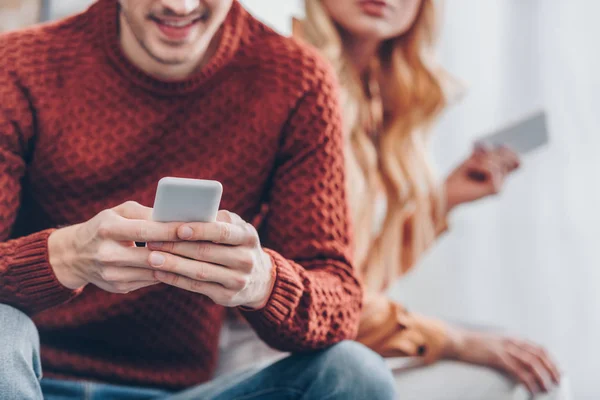 Schnappschuss von lächelndem Mann und junger Frau mit Smartphones zu Hause, Misstrauen Konzept — Stockfoto
