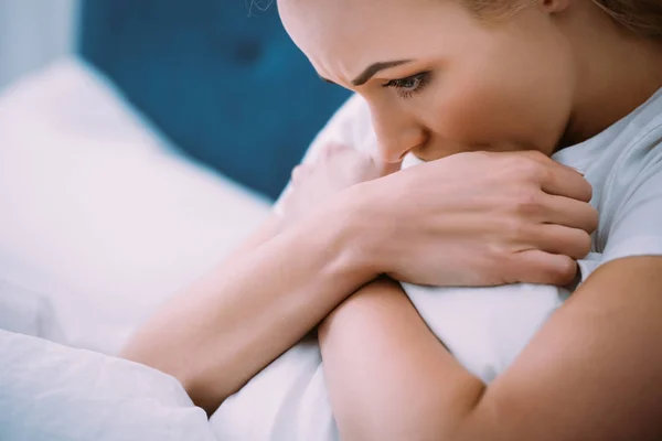 Enfoque selectivo de la mujer estresada sosteniendo la manta mientras está acostada en la cama en casa - foto de stock