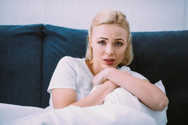 Verängstigte Frau hält Decke in der Hand und blickt zu Hause im Bett in die Kamera — Stockfoto