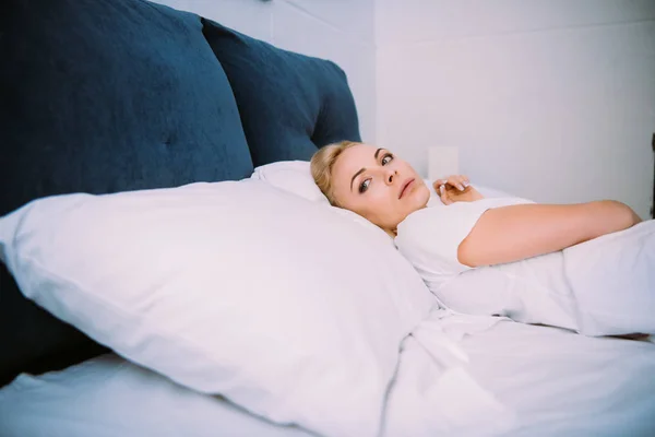 Красивая грустная женщина лежит в постели и смотрит в сторону — стоковое фото