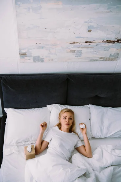 Расстроена женщина лежит с коробкой ткани в постели дома — стоковое фото