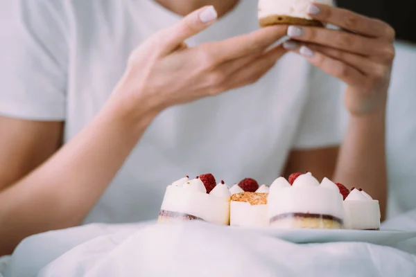 Vista ritagliata di donna mangiare torta a letto — Foto stock