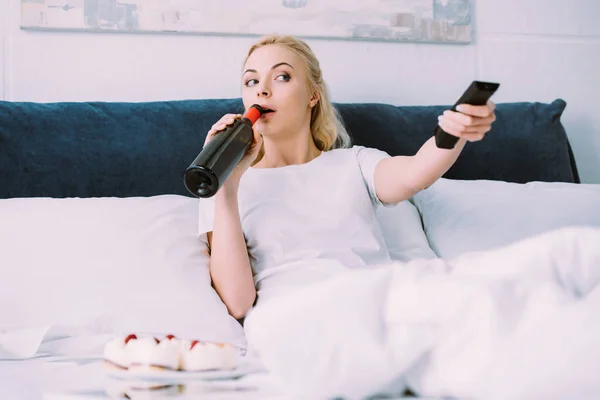 Frau trinkt Wein und schaut Fernsehen, während sie Geburtstag allein im Bett feiert — Stockfoto