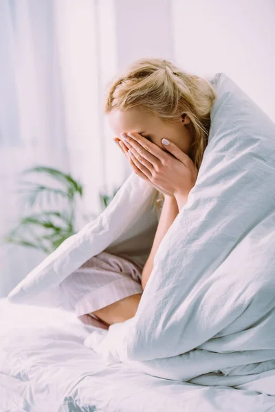 Frau in Decke bedeckt Gesicht mit Händen und weint zu Hause im Bett — Stockfoto