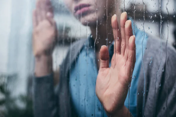 Abgeschnittene Ansicht einer erwachsenen Frau zu Hause, die Fenster mit Regentropfen berührt — Stockfoto