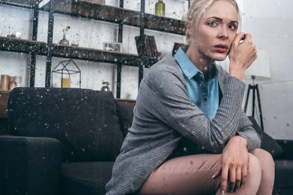 Femme adulte triste toucher le visage et regarder loin à la maison par la fenêtre avec des gouttes de pluie — Photo de stock