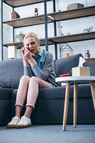 Traurige Frau sitzt auf Couch und weint im Wohnzimmer — Stockfoto