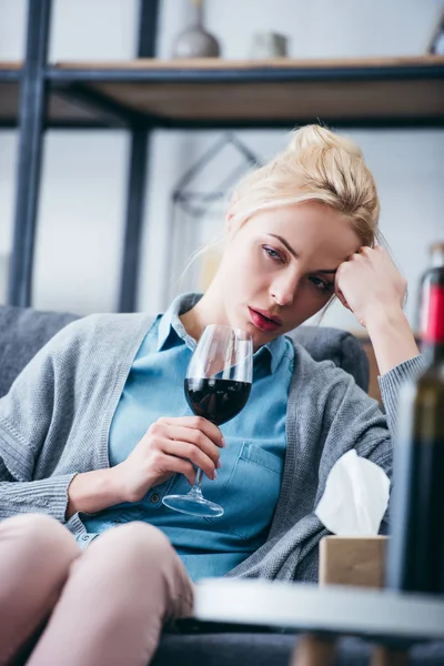 Mulher chateada sentado com copo de vinho tinto e caixa de tecido em casa — Fotografia de Stock