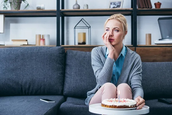 Bela mulher enxugando lágrimas e chorando enquanto celebra aniversário em casa sozinha — Fotografia de Stock