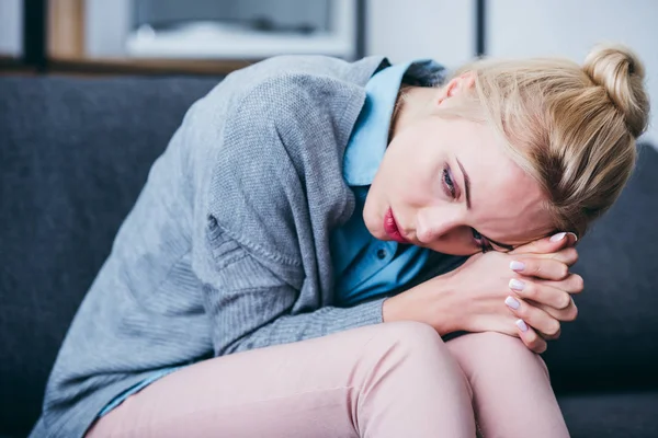 Femme déprimée avec les mains pliées assis à la maison et regardant loin — Photo de stock