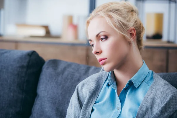 Selective focus of beautiful upset woman sitting on couch at home — Stock Photo