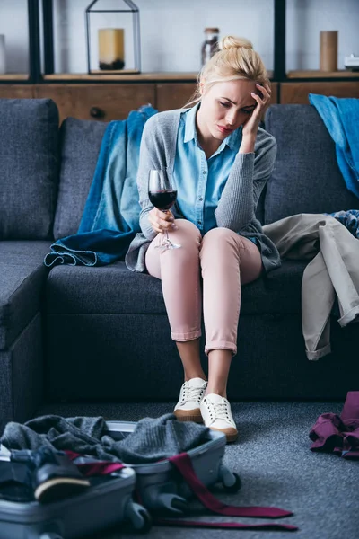 Sad woman sitting with glass of red wine while packing in living room after breaking up with boyfriend — Stock Photo