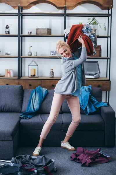 Femme irritée jetant des vêtements dans le salon après avoir rompu avec son petit ami — Photo de stock