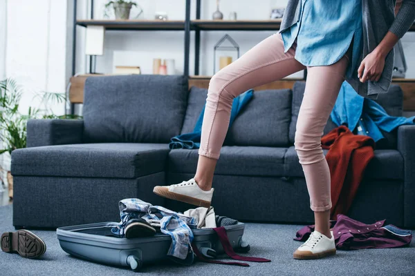 Ausgeschnittene Ansicht von Frau, die nach Trennung von Freund Kleidung in Koffer mit Bein schiebt — Stockfoto