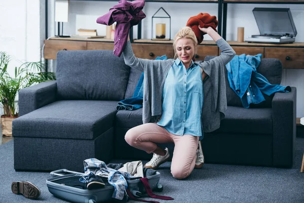 Frustrated woman throwing clothes in living room after breaking up with boyfriend — Stock Photo