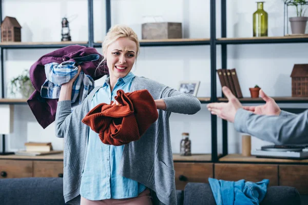 Wütende Frau wirft nach Trennung von Freund Kleidung ins Wohnzimmer — Stockfoto