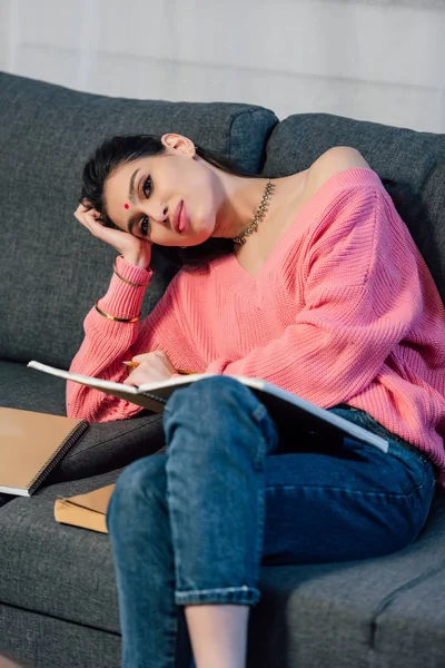 Müder indischer Student mit Bindi, der zu Hause mit Notizbüchern lernt — Stockfoto