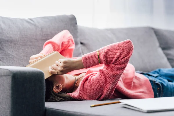Exhausted indian student lying on sofa with book — Stock Photo