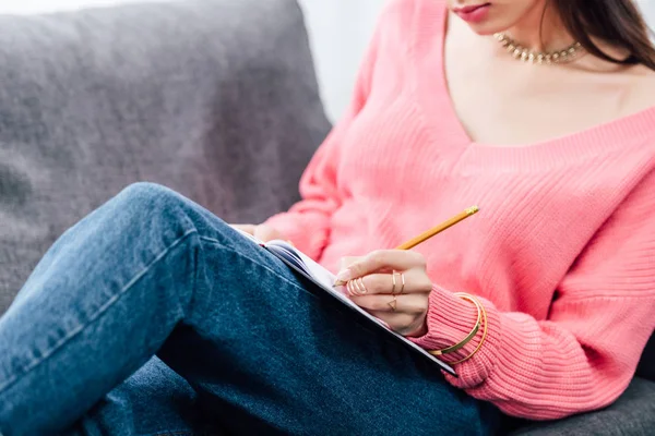 Vista recortada de la escritura del estudiante femenino en el cuaderno - foto de stock