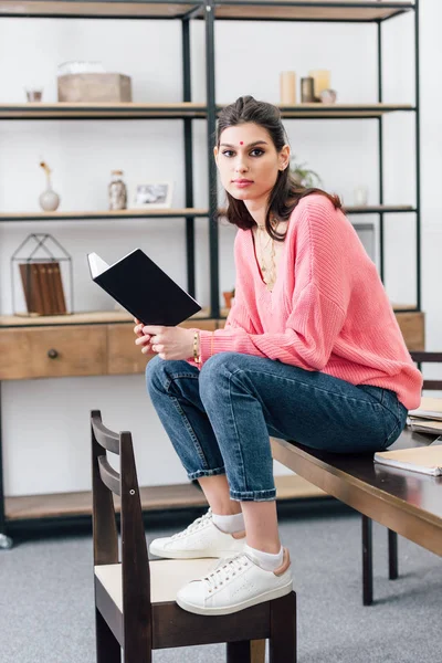 Beautiful indian student with bindi studying with notebook at home — Stock Photo