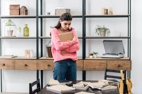 Sad indian student with bindi looking at notebooks at home — Stock Photo