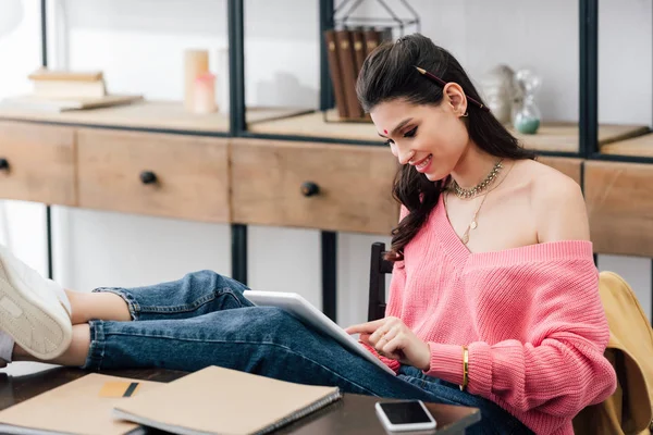 Mujer india sonriente con bindi estudiando con tableta y libros - foto de stock