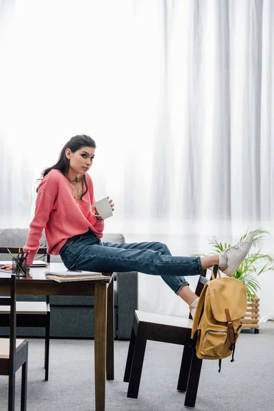 Thoughtful indian student holding cup of coffee at home — Stock Photo