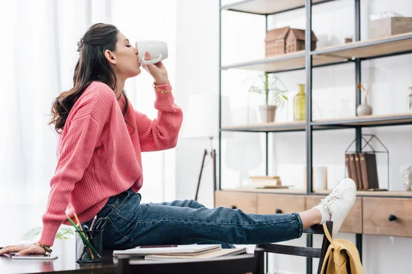 Indian student drinking coffee at home with notebooks — Stock Photo