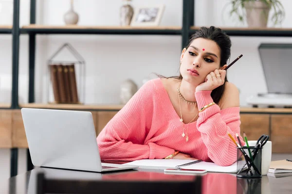 Pensive indian woman with bindi studying with laptop at home — Stock Photo