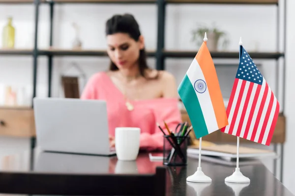 Enfoque selectivo de banderas americanas e indias en la mesa y la niña que estudia con el ordenador portátil - foto de stock