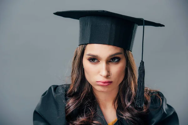 Upset female indian student in black graduation cap, isolated on grey — Stock Photo