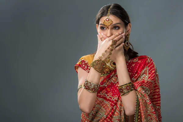 Beautiful indian woman closing mouth with hands, isolated on grey — Stock Photo