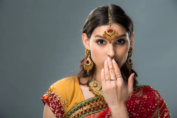 Здивована індійська жінка закриває рот, ізольована на сірому — стокове фото