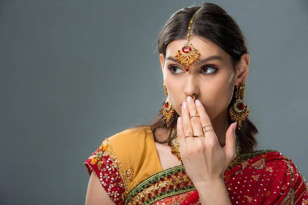 Шокована приваблива індійська жінка закриває рот, ізольована на сірому — стокове фото