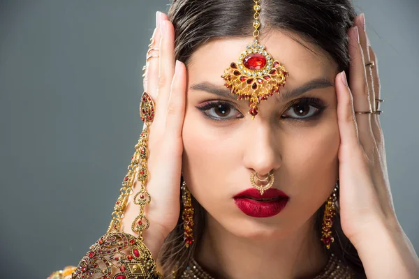 Hermosa mujer india con bindi tocando la cabeza, aislado en gris - foto de stock