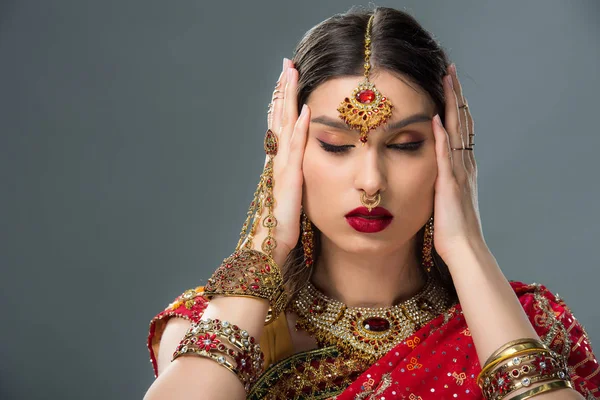 Attractive indian woman with bindi touching head, isolated on grey — Stock Photo