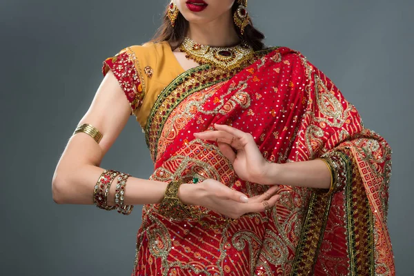 Ausgeschnittene Ansicht einer attraktiven indischen Frau, die in traditioneller Kleidung gestikuliert, isoliert auf grau — Stockfoto