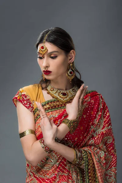 Приваблива індійська жінка позує в традиційному одязі, показуючи мудра, ізольована на сірому — стокове фото