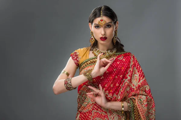 Привлекательная индийская женщина в традиционной одежде, на которой изображена Сюня Мудра, изолированная на сером — стоковое фото