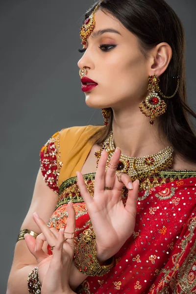 Привлекательная индийская женщина в традиционной одежде, изображающая гьянскую мудру, изолированную на сером — стоковое фото