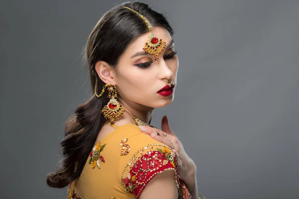 Elegante Indianerin posiert in traditionellem Sari und Accessoires, isoliert auf grau — Stockfoto