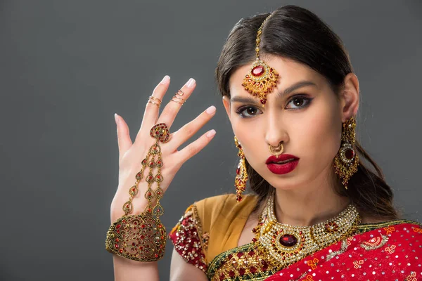 Bela mulher gesticulando em sari indiano tradicional e acessórios, isolado em cinza — Fotografia de Stock