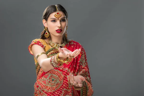 Indianerin gestikuliert in traditionellem Sari und Accessoires, isoliert auf grau — Stockfoto