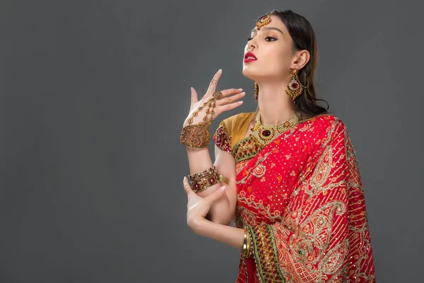 Attractive indian woman gesturing in traditional sari and accessories, isolated on grey — Stock Photo