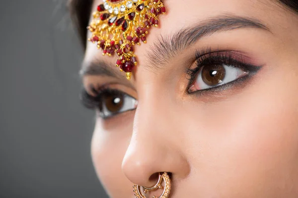 Primer plano de la mujer india posando en accesorios tradicionales, aislado en gris - foto de stock