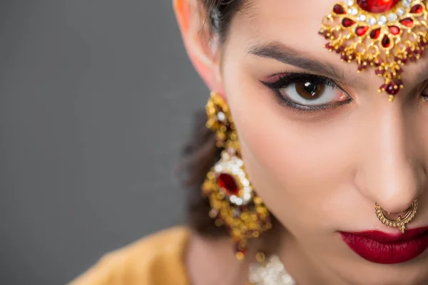 Nahaufnahme einer indischen Frau, die in traditionellen Accessoires posiert, isoliert auf grau — Stockfoto
