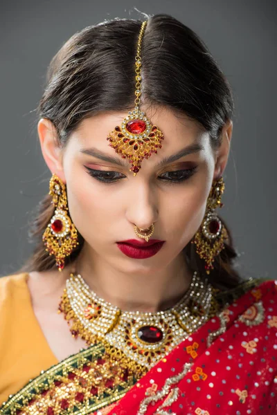 Attraktive Indianerin posiert in traditionellem Sari und Schmuck, isoliert auf grau — Stockfoto