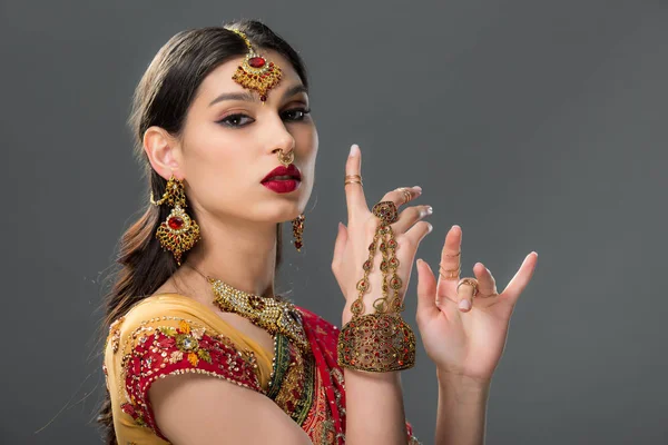 Elegante Indianerin gestikuliert in Sari und Accessoires, isoliert auf grau — Stockfoto
