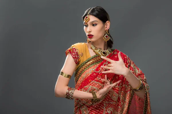 Attraktive Indianerin gestikuliert in Sari und Accessoires, isoliert auf grau — Stockfoto