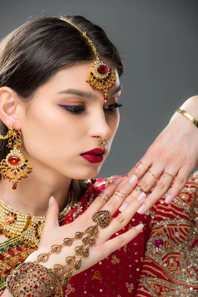 Mulher indiana atraente gesticulando em acessórios tradicionais, isolado em cinza — Stock Photo